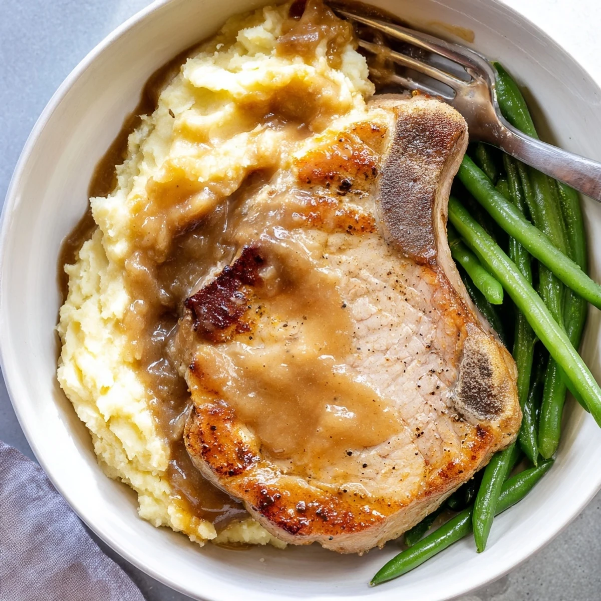 Juicy pork chops served over creamy cheddar mash with savory gravy drizzle.