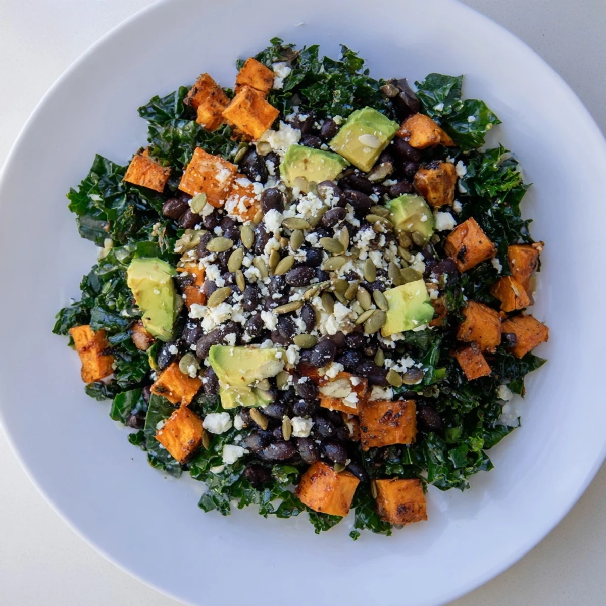 Massaged kale salad with sweet potato, black beans, and lime dressing, a colorful and healthy lunch.