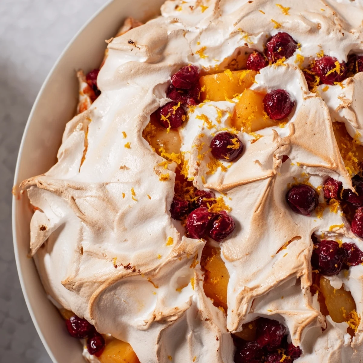 A warm, inviting photo of the festive Cranberry and Pear Snowscape dessert with fluffy meringue peaks.