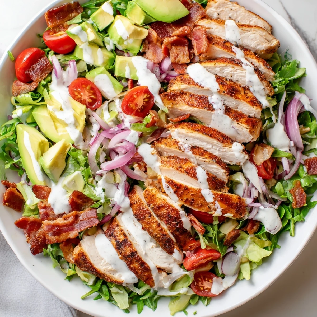 Close-up of a delicious and hearty Crispy Bacon Chicken Salad, perfect with bacon crumbles and cheddar cheese.