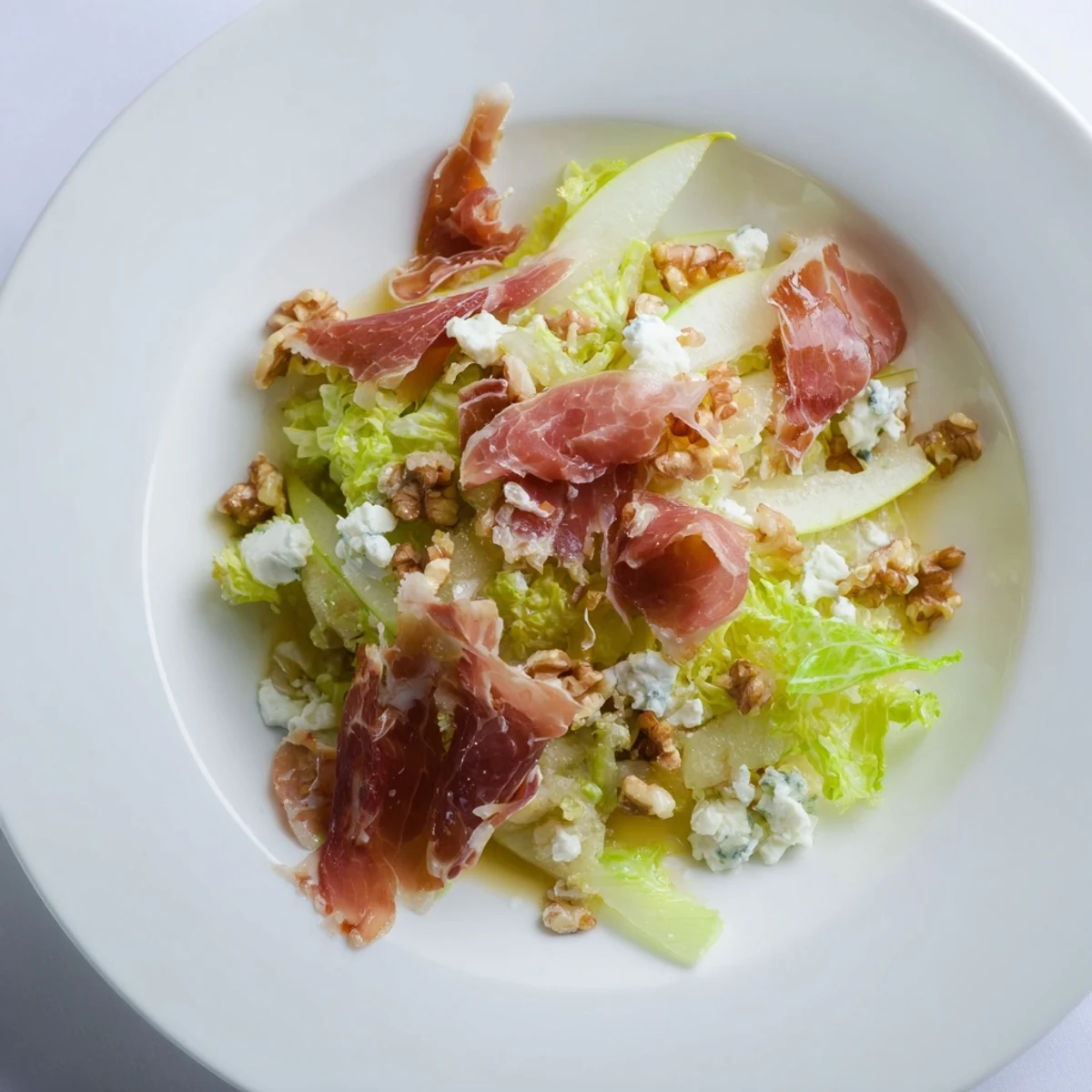 Salad featuring frisée, pear, blue cheese, and crispy prosciutto for a tasteful bite.