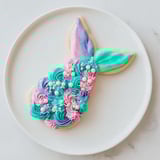 Close-up of freshly frosted mermaid tail sweets: edible shimmer and candy pearls make these desserts magical.