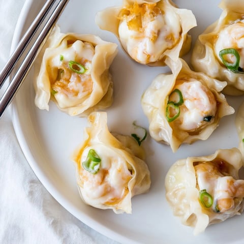 Close-up of freshly steamed, savory Cheesy Shrimp Scallion Dumplings ready for a dipping sauce.
