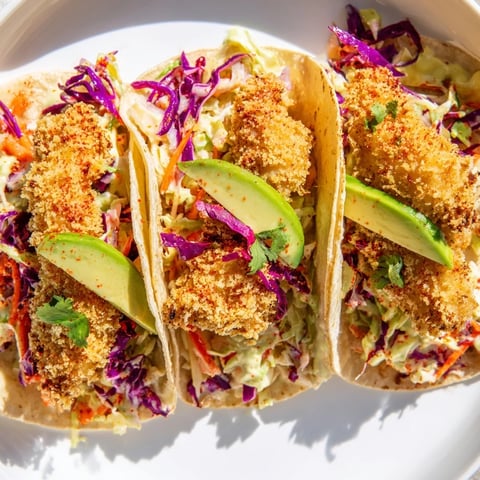 Golden-brown, crispy fish tacos overflowing with fresh slaw, ready for a satisfying, flavorful bite.