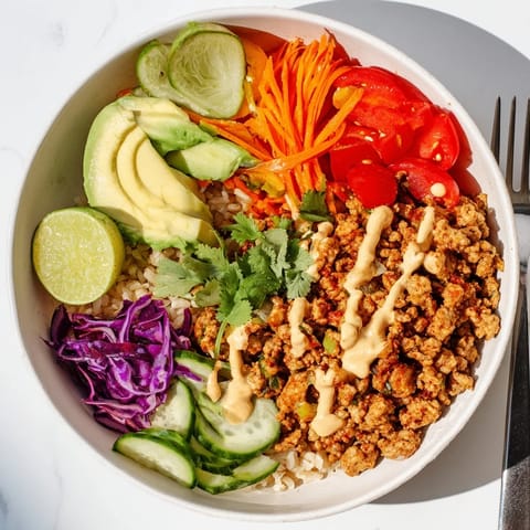 Colorful plant-based meat bowl with avocado, carrots, and lime wedges for zest.  
