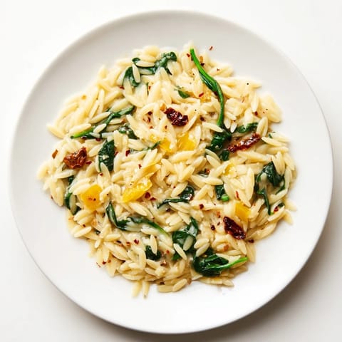 This Creamy Tuscan Orzo Bowl features an inviting swirl of rich Parmesan and wilted spinach.
