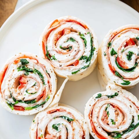 Creamy filling bursting from vibrant Christmas Scarf Tortilla Roll-Ups makes the ideal party snack.