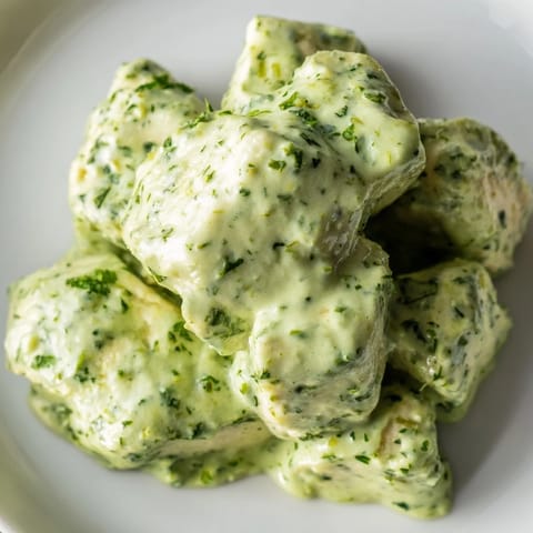 Hearty Green Goddess chicken salad in a white bowl, vibrant herbs and greens topped with tender chicken and ripe avocado.