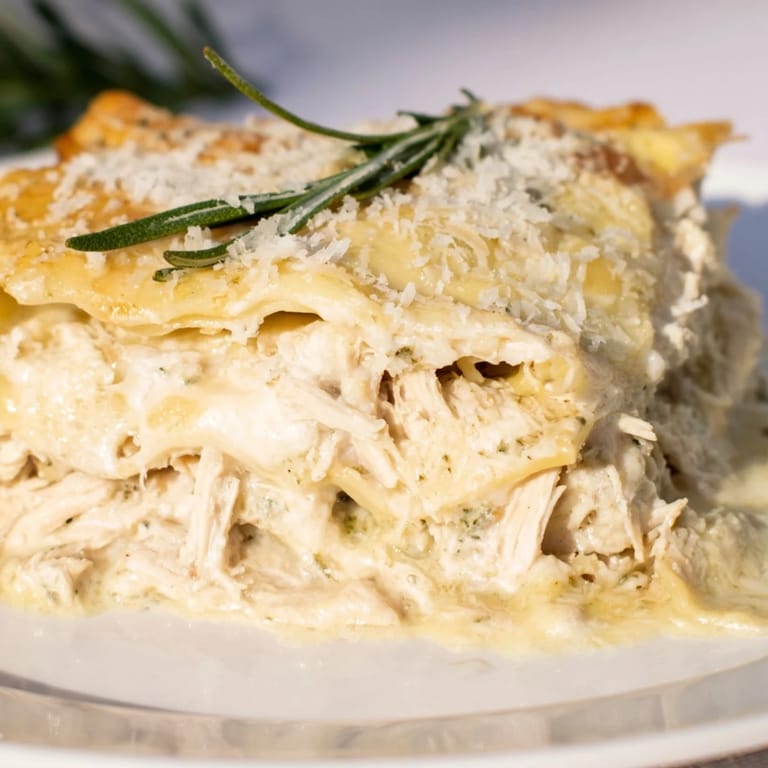 A close-up shot of creamy Rosemary Chicken Lasagna, layered with cheese and herbs, ready to serve.