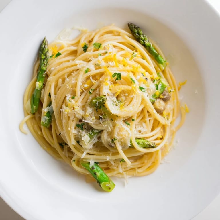 Overhead view of Roasted Garlic & Asparagus Pasta on a rustic table, showing spaghetti tossed with roasted asparagus and aromatic garlic cloves.